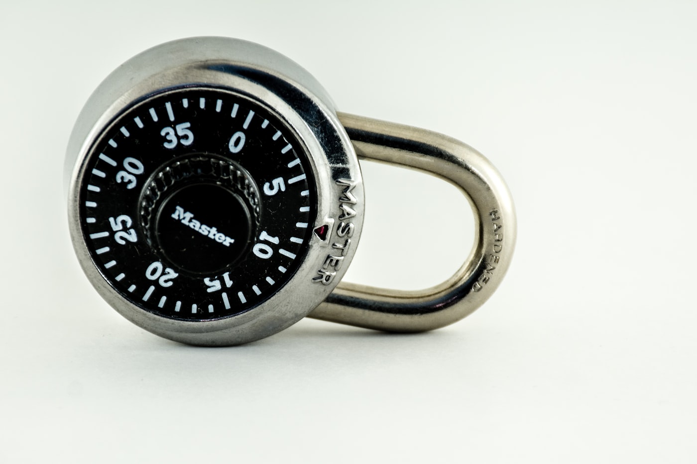 A heavy steel padlock locked shut against a metallic surface, dark moody lighting